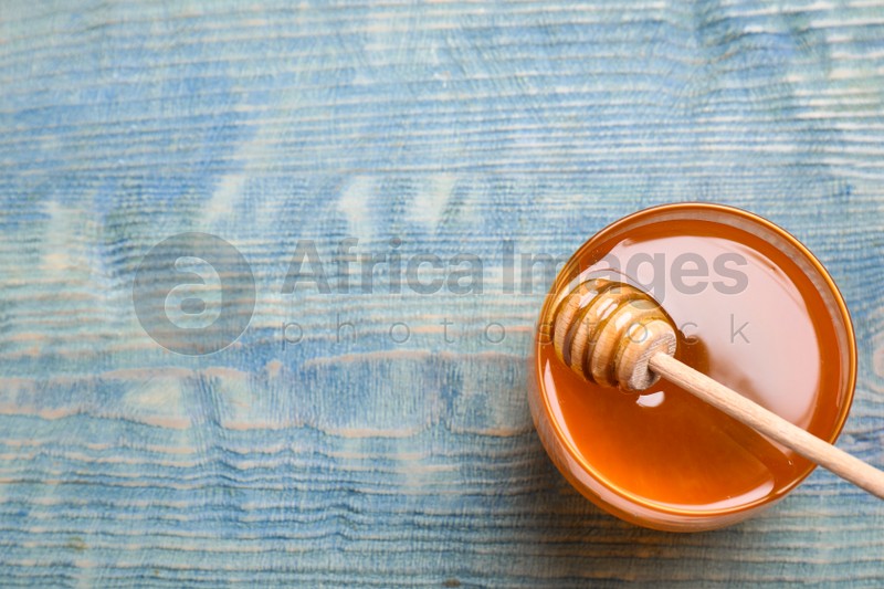 Photo of Tasty honey on light blue wooden table, top view. Space for text