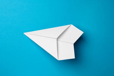 Handmade white paper plane on light blue background, top view