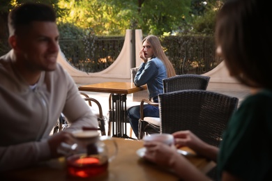 Jealous ex girlfriend spying on couple in outdoor cafe