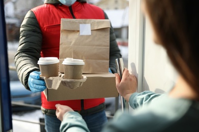 Courier giving to woman her order at doorway, closeup. Delivery service during Covid-19 quarantine