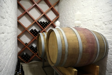 Wooden barrels on stand near white brick wall in wine cellar