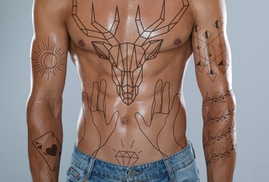 Handsome man with beautiful tattoo sketches on light background, closeup