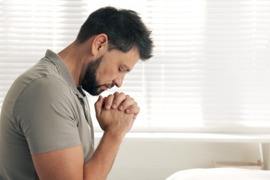 Religious man praying indoors. Space for text