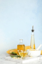 Bottles and gravy boat with fresh corn oil on table against color wall