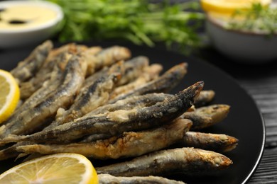 Photo of Plate with delicious fried anchovies and slices of lemon, closeup