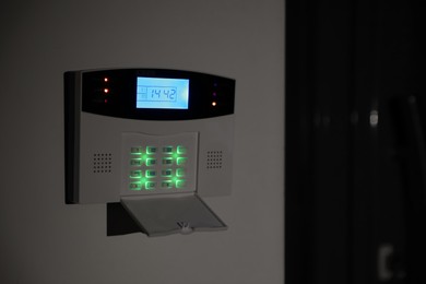Home security alarm system on white wall, space for text