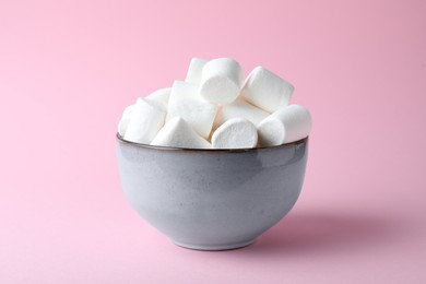 Delicious puffy marshmallows in bowl on pink background