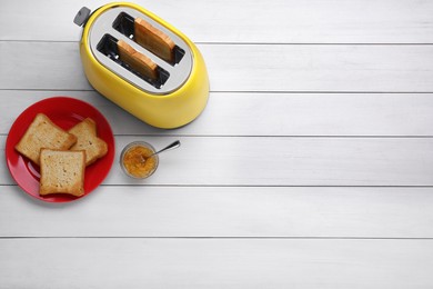 Photo of Yellow toaster with roasted bread and jam on white wooden table, flat lay. Space for text