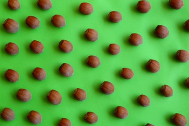 Photo of Brown tasty hazelnuts on green background, flat lay