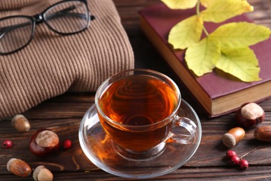 Photo of Cup of aromatic tea, book and soft sweater on wooden table indoors, above view. Autumn atmosphere
