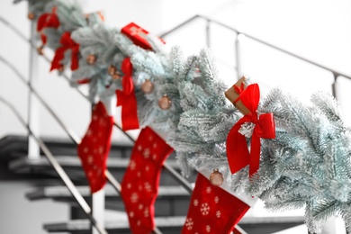 Santa stockings and garland on railing indoors. Christmas decor idea