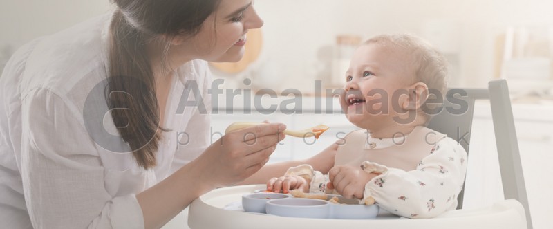 Mother feeding her cute little baby in kitchen. Banner design