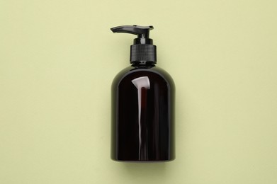 Bottle of shampoo on light green background, top view