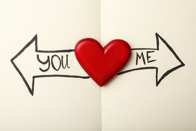 Heart between arrows with words YOU and ME pointing in different directions on notepad, top view. Composition symbolizing relationship problems