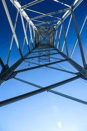Modern high voltage tower against blue sky, bottom view