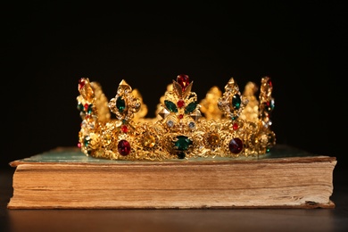Beautiful golden crown on old book against black background. Fantasy item