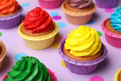 Many delicious colorful cupcakes and confetti on violet background, closeup