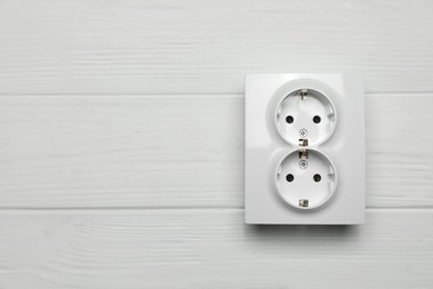 Modern plastic power socket on white wooden table, top view. Space for text