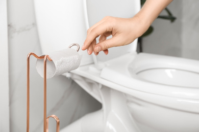 Woman reaching for empty toilet paper roll in bathroom, closeup