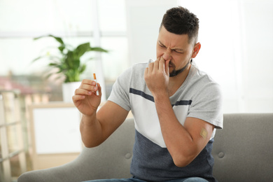 Emotional man with nicotine patch and cigarette at home