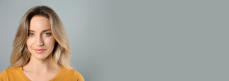 Image of Portrait of happy young woman with beautiful blonde hair on grey background, space for text. Horizontal banner design