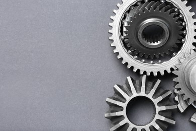 Photo of Many different stainless steel gears on grey background, flat lay. Space for text
