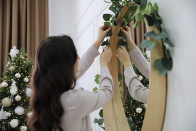 Woman decorating mirror with eucalyptus branches at home
