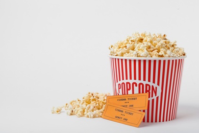 Bucket of fresh popcorn and tickets on white background. Cinema snack