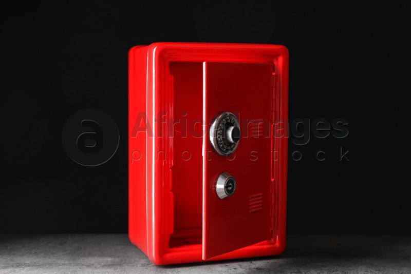 Red steel safe on grey stone table against black background