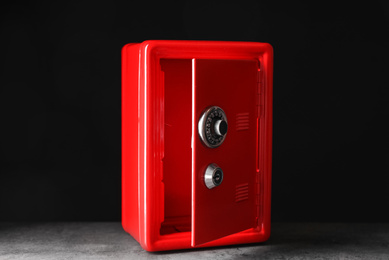 Red steel safe on grey stone table against black background