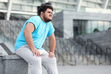 Young overweight man in sportswear resting outdoors