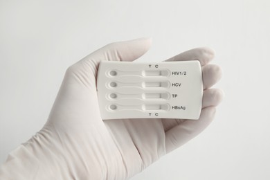 Doctor holding disposable express test for hepatitis on white background, closeup
