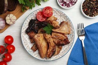 Photo of Tasty fried pork lard with parsley and tomatoes on white wooden table, flat lay