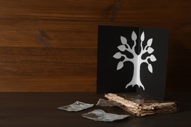 Card with family tree template, photos and album on wooden table. Space for text