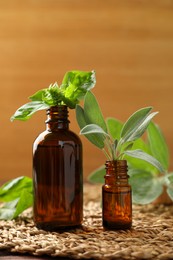 Bottles of essential oils and fresh herbs on wooden table