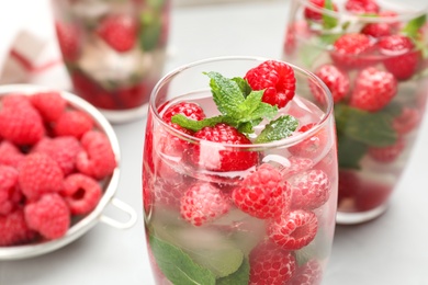 Glass of refreshing drink with raspberry and mint on grey table, closeup view