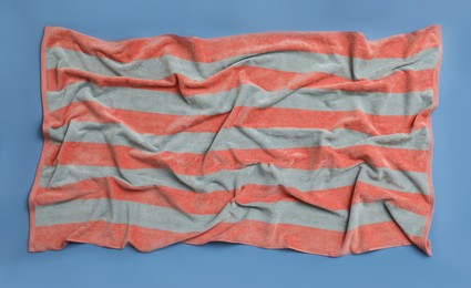 Crumpled striped beach towel on blue background, top view