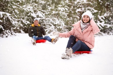 Happy couple sledding outdoors on winter day. Christmas vacation