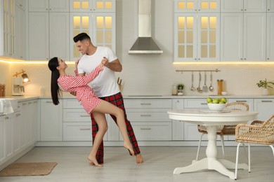 Photo of Happy couple wearing pyjamas and dancing in kitchen