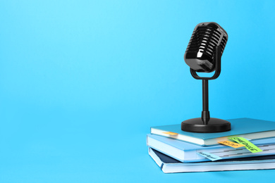 Retro microphone and notebooks on light blue background, space for text. Job interview