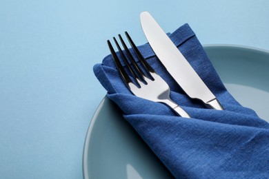 Beautiful table setting on light blue background, closeup. Space for text