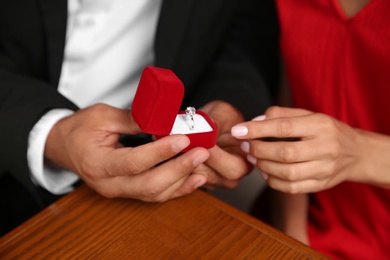 Man with engagement ring making proposal to his girlfriend at table, closeup