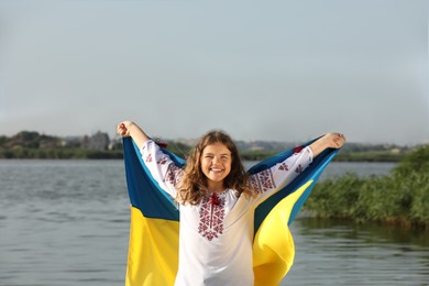 Teenage girl in vyshyvanka with flag of Ukraine outdoors