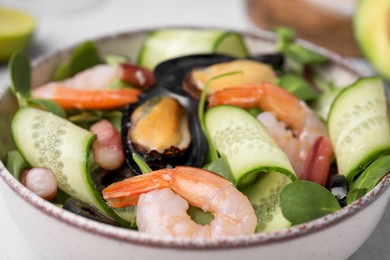 Photo of Bowl of delicious salad with seafood, closeup view