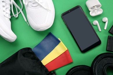 Flat lay composition with fitness elastic bands on green background