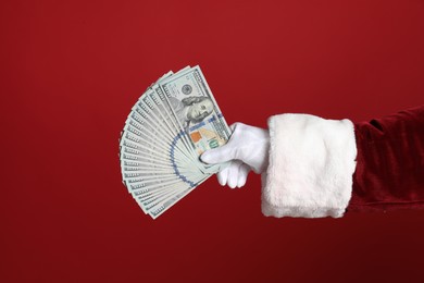 Photo of Santa holding dollar bills on red background, closeup
