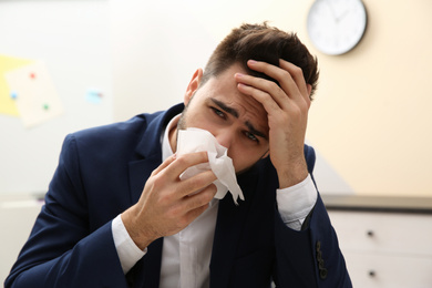 Sick young man at workplace. Influenza virus