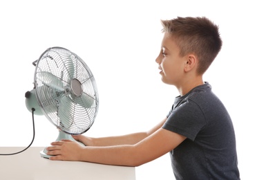 Little boy enjoying air flow from fan on white background. Summer heat