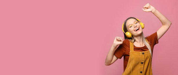 Young woman listening to music with headphones on pink background, space for text. Banner design