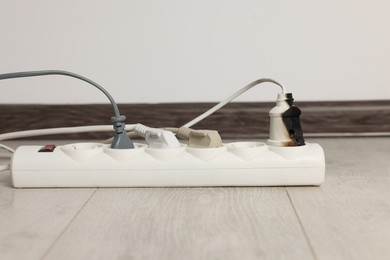Photo of Burnt plug in power strip indoors. Electrical short circuit